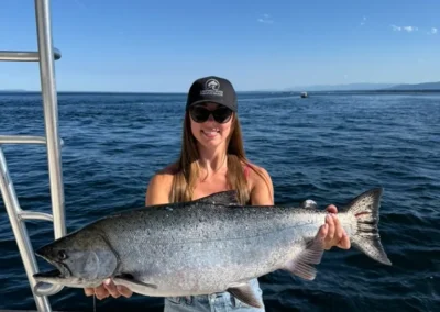 Woman holding massive salmon she just caught with Campbell River Fishing Guide