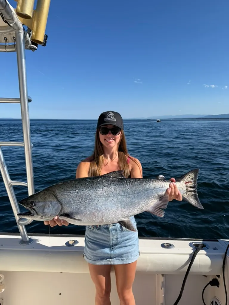 Woman holding massive salmon she just caught with Campbell River Fishing Guide